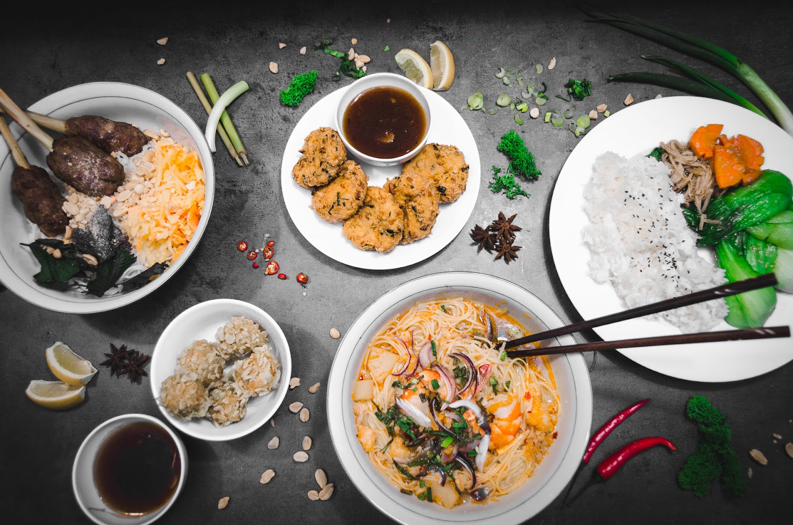 Pestrá hostina vietnamských specialit na tmavém pozadí.