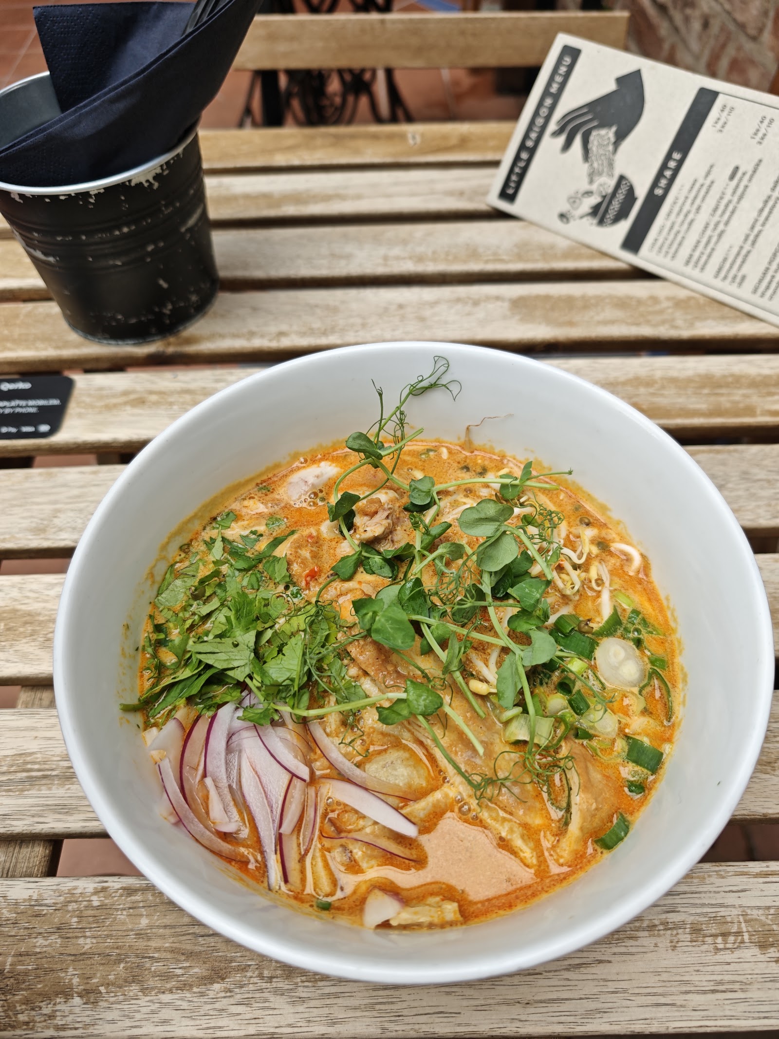 Krémová laksa polévka s čerstvými bylinkami a cibulí.